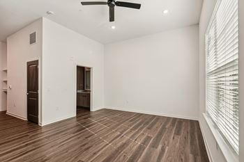 A room with a ceiling fan and wooden flooring